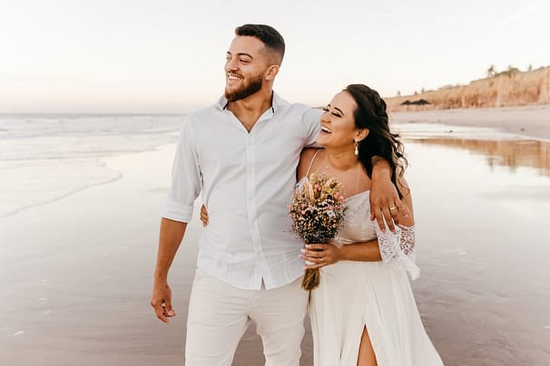 delighted newlywed couple walking on beach